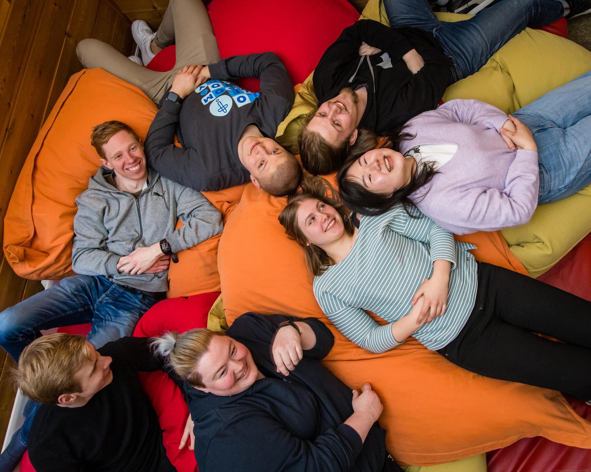 Ungdommer ligger på saccosekker og ser opp i kamera